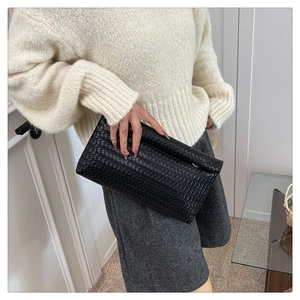 Dettaglio della borsa a mano intrecciata nera con texture in pelle e design minimalista