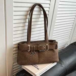 Brown textured rectangular shoulder bag with silver hardware on a leather sofa