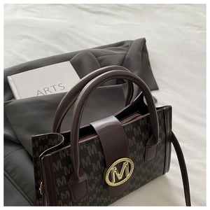 Dettaglio della borsa marrone con motivi monogramma 'M' e fibbia metallica dorata