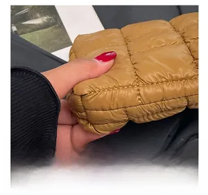 Detailed close-up of precise quilting and caramel nylon fabric on the puffer bag