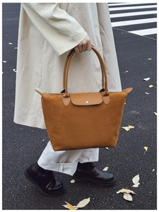 Close-up of caramel suede tote bag with leather straps and metal buckle on street