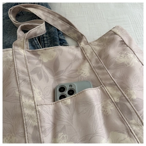Detail of floral canvas tote bag showing exterior front pocket with a smartphone inside