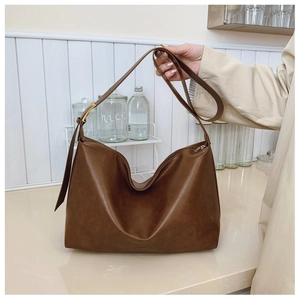 Detail of dark brown tote bag with adjustable shoulder strap and gold metal buckle