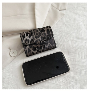 Mini leopard print card holder shown next to a smartphone to demonstrate its compact size