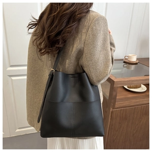Detail of black leather bucket bag with gold hardware and adjustable shoulder strap