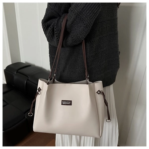 Close-up of minimalist cream tote bag with dark brown straps and drawstring detail
