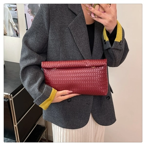 Dettaglio della pochette rossa in pelle intrecciata con fibbia ad anello in metallo