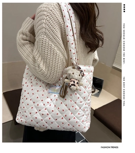 Quilted tote bag with red heart pattern featuring a plush cat charm shown from the side