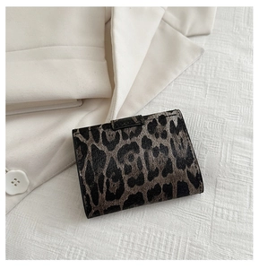 Close-up of mini leopard print wallet on white textured background with suit detail