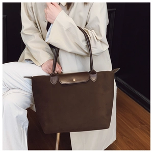 Close-up of a dark brown large-capacity tote bag with leather handles and gold metal snap