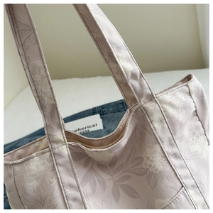 Close-up of floral canvas tote handle stitching and secure zipper closure details