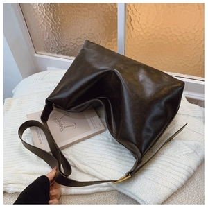 Detail of black PU leather hobo bag with adjustable strap on white knit fabric