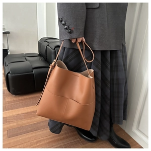 Close-up of caramel brown leather bucket bag showing side profile and stitch detail