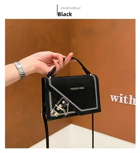 Detail view of black suede crossbody bag with white V-stitching and gold metal clasp