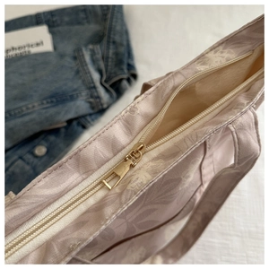 Close-up of golden metal zipper and floral fabric on a stylish tote handbag
