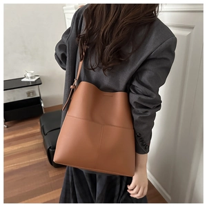 Brown leather bucket bag detail showing large capacity and contrast stitching on shoulder