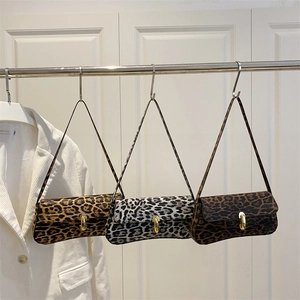 Three leopard print underarm bags with gold buckles shown on a clothing rack