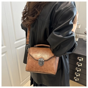 Sac à main vintage en cuir synthétique marron avec boucle en métal porté par mannequin