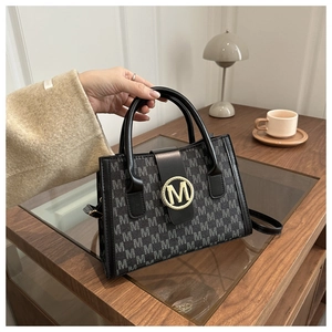 Dettaglio borsa tote jacquard grigia con fibbia logo M dorata su scrivania in legno