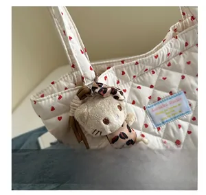 Detail of plush leopard-print bear charm hanging on a white quilted heart-shaped tote bag