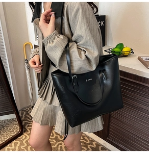 Close-up of black PU leather tote bag with silver brand logo and wrinkled texture details