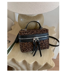 Détail du sac boîte à motif léopard avec franges en cuir sur une table en pierre