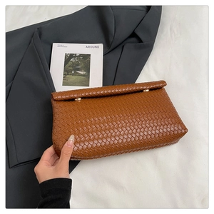 Dettaglio della trama intrecciata marrone su una borsa clutch minimalista con patta