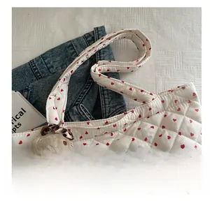 Detailed texture of white quilted tote bag with red hearts and plush cat keychain