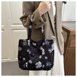 Detail of black canvas tote bag with white floral art print and practical front pocket