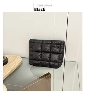 Detail of black puffer bag featuring quilted fabric on a modern glass display stand