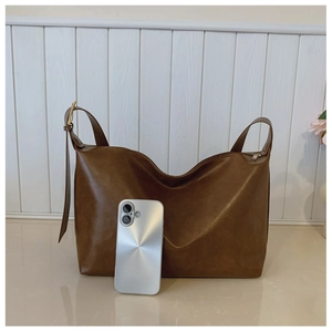 Detail view of large brown hobo tote with smooth matte leather and adjustable metal buckle