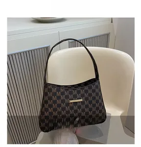 Close-up of M-pattern monogram bucket bag with gold metal clasp on a cream chair