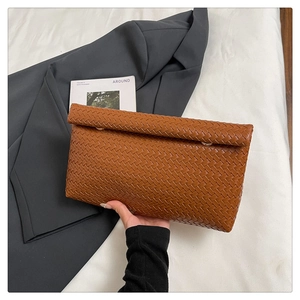 Dettaglio della pochette intrecciata marrone caramello con struttura a busta premium