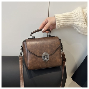 Detail view of vintage brown crossbody bag with distressed leather texture and metal lock