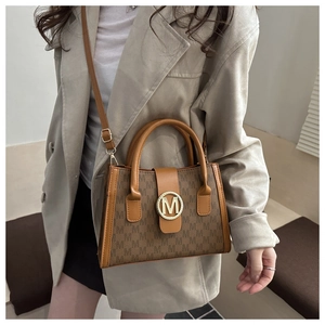 Dettaglio di una borsa a tracolla monogramma marrone con fibbia dorata a cerchio M