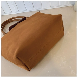 Detail view of caramel brown tote bag with premium faux suede texture and leather handles