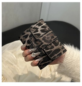 Close-up of leopard print PU leather mini wallet with flap closure held in hand