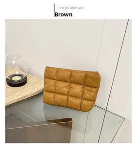 Detail of brown quilted puffy clutch with soft satin finish on glass tabletop