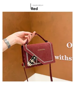 Detail of red suede crossbody bag featuring gold hardware and v-shaped stitching detail