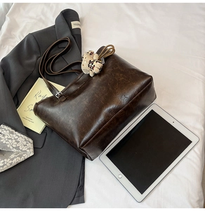 Detail of dark brown vintage tote bag with leopard charm near office essentials
