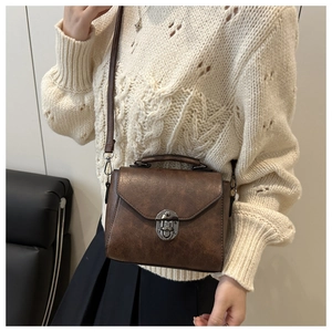 Close-up of vintage brown leather crossbody bag featuring a dark grey metal buckle