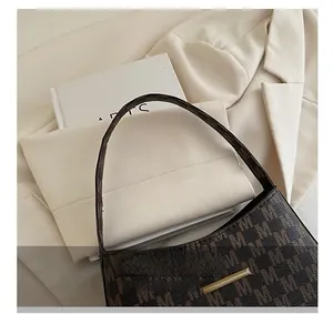 Detail of dark brown monogram shoulder bag with metallic gold buckle on blazer background
