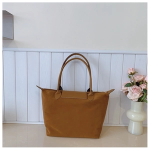 Detailed view of brown suede tote bag with leather flap and sturdy shoulder straps
