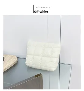Detail of creamy white quilted handheld clutch bag with soft puffer nylon texture