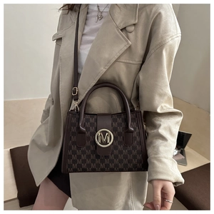 Dettaglio del motivo monogramma marrone scuro e della fibbia in metallo dorato sulla borsa