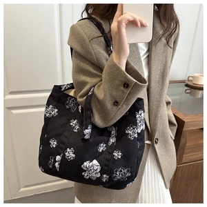 Close-up of black canvas tote bag with white floral pattern during mirror selfie