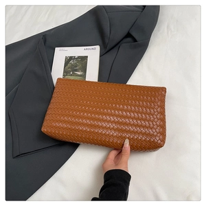 Dettaglio pochette in pelle intrecciata marrone caramello con motivo a rombi testurizzato