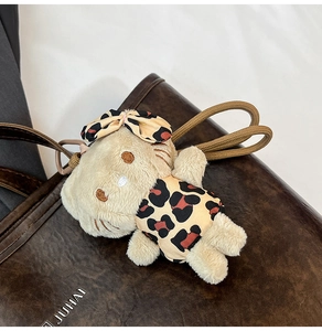 Detail of Hello Kitty plush charm in leopard print outfit on a brown leather tote bag