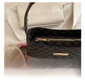 Close-up of smooth gold zipper and monogram pattern on dark brown handbag
