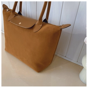 Detail of tan tote bag with suede texture and leather handle showing zip and snap button